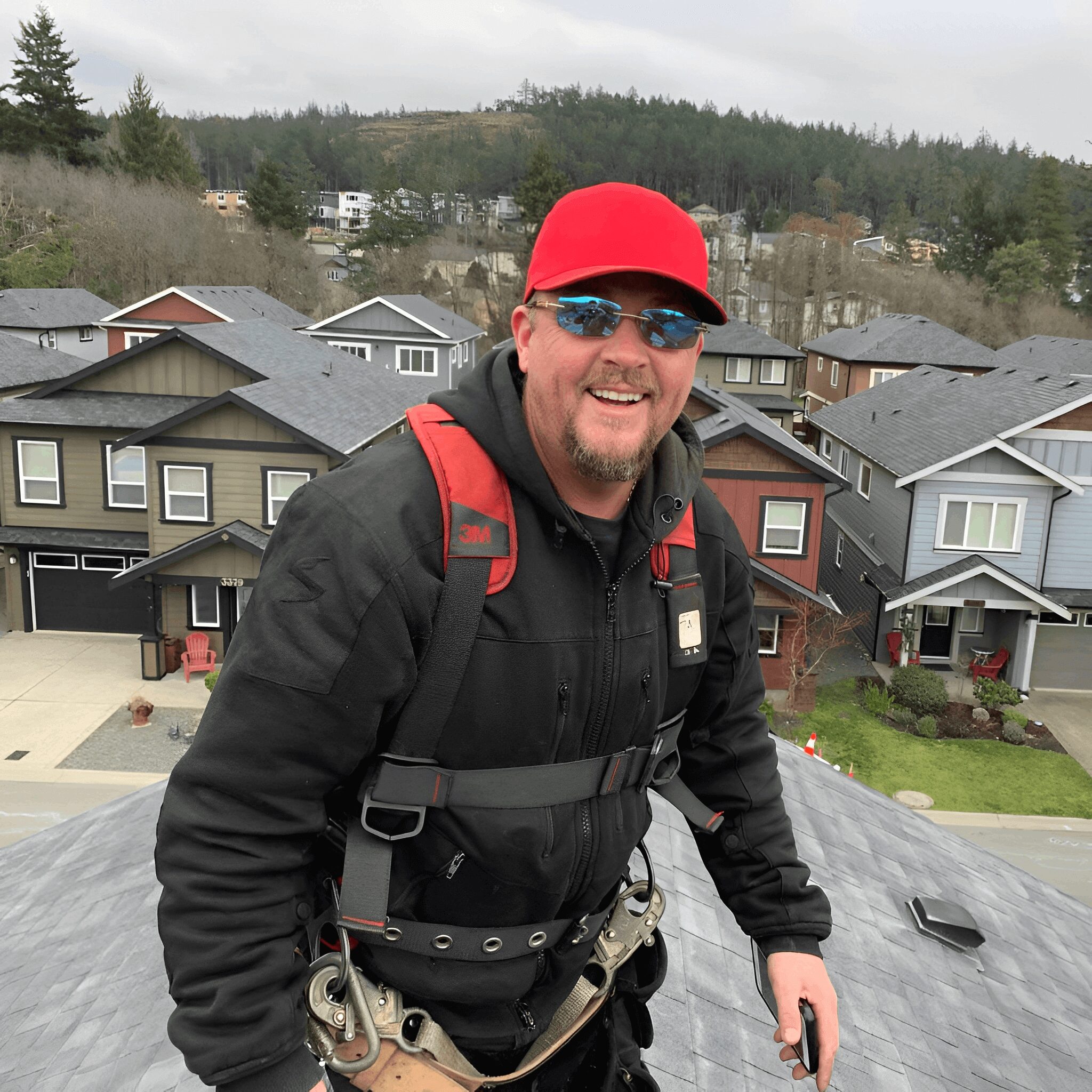 Worker on rooftop wearing safety gear and smiling.
