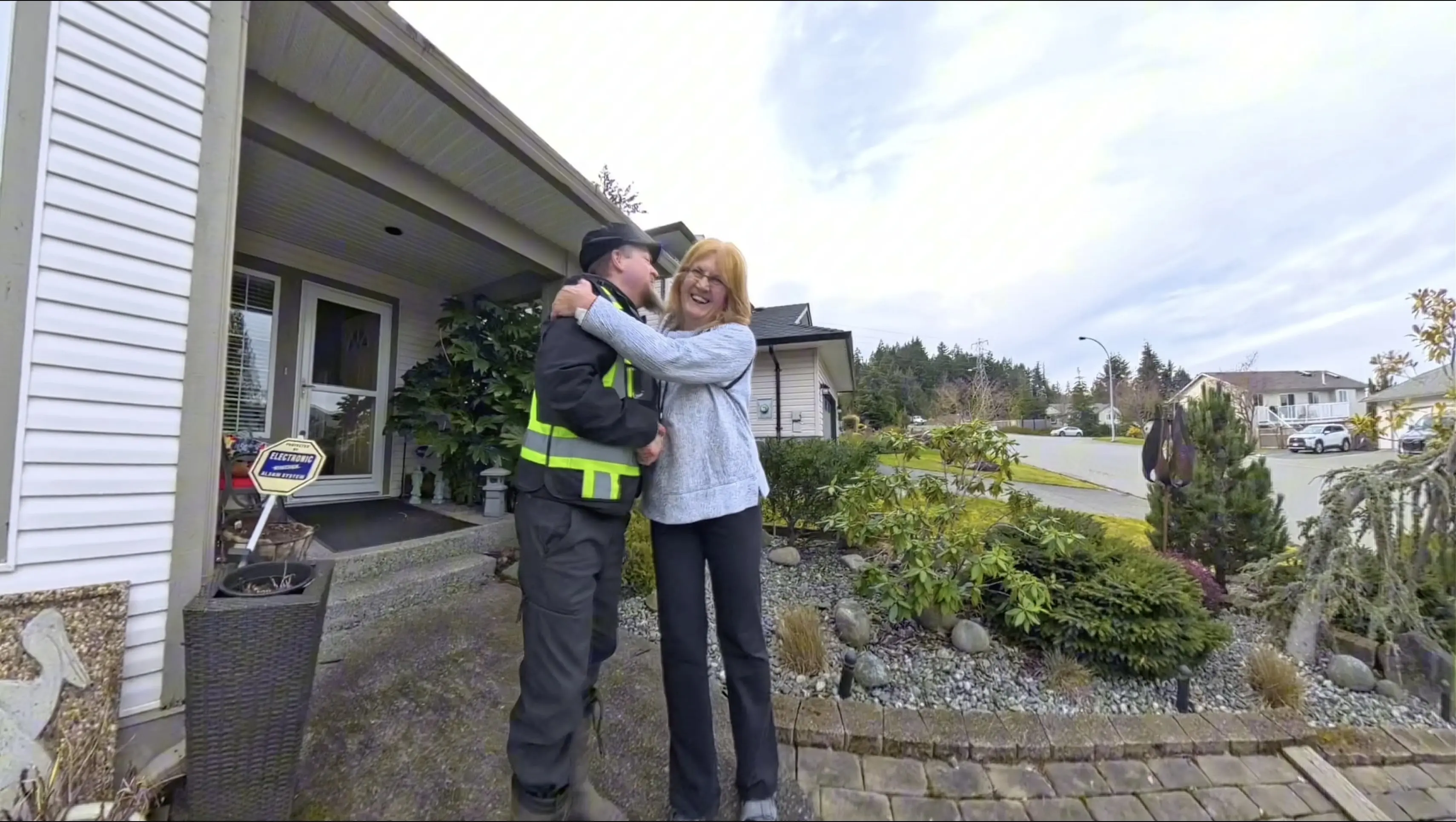 A woman hugging a man in front of a house.